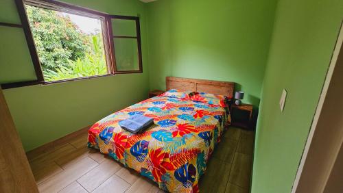 ein Schlafzimmer mit einem Bett mit einer bunten Decke und einem Fenster in der Unterkunft Kaz Anthurium in Saint-Benoît