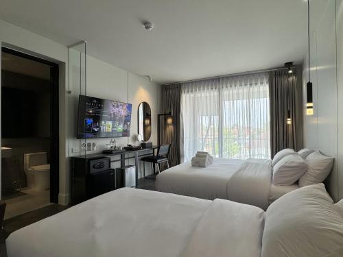 a hotel room with two beds and a television at POR Singharat in Chiang Mai