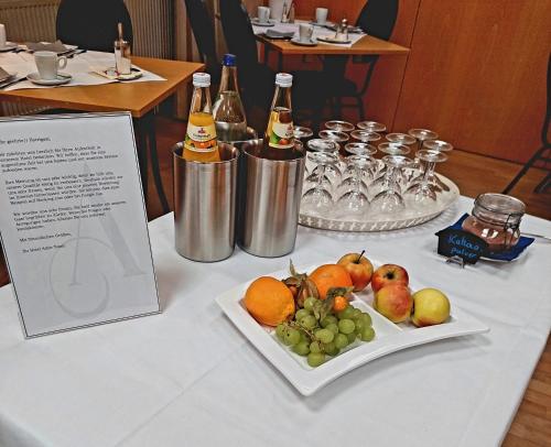 uma mesa com um prato de frutas e garrafas de champanhe em Hotel & Gastro Adler GmbH em Itzehoe