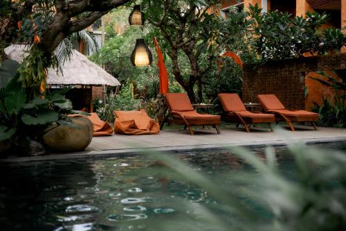 a group of chairs sitting next to a swimming pool at Fourteen Roses Boutique Hotel, Kuta in Legian