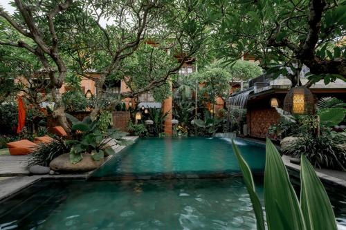 a swimming pool in a garden with trees and plants at Fourteen Roses Boutique Hotel, Kuta in Legian