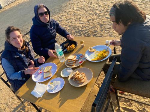 een groep mensen die aan een tafel zitten met eten bij Tokyo Desert Camp in Sām