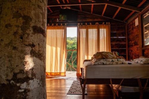 ein Schlafzimmer mit einem Bett und einem großen Fenster in der Unterkunft Moradia da Mata in Nilo Peçanha