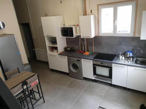 uma cozinha com armários brancos, um lavatório e uma máquina de lavar louça em Villa proche JO 2024 em La Courneuve