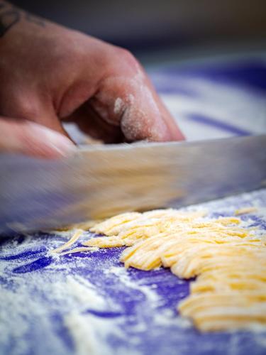 a person cutting pasta with a knife on a table at Zamek Międzylesie in Międzylesie
