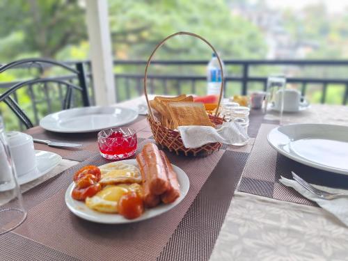 a table with a plate of food and a basket of bread at Jaye's Homestay in Kandy