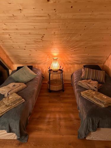 a room with two beds and a lamp in a log cabin at Sauna House Smyczyna in Smyczyna