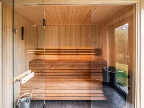 a glass walled sauna with a bench and a window at Blue Seas in Mawgan Porth