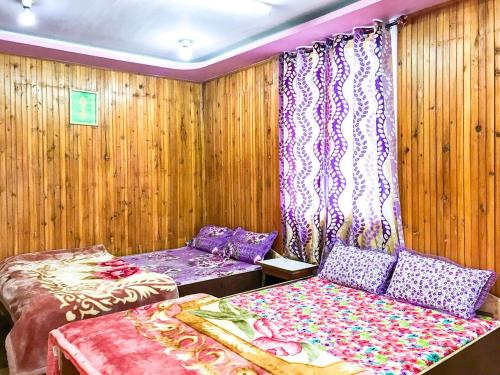 two beds in a room with wooden walls and curtains at BODHI VILLA in Sombāri