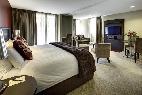 a hotel room with a large bed and a living room at Rendezvous Heritage Hotel Queenstown in Queenstown
