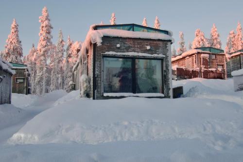 a building covered in snow with trees in the background at Polaris Igloo Levi in Levi