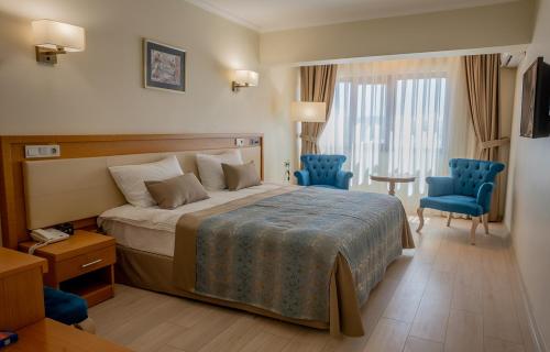 a hotel room with a bed and two blue chairs at Patalya Lakeside Resort Hotel in Golbası