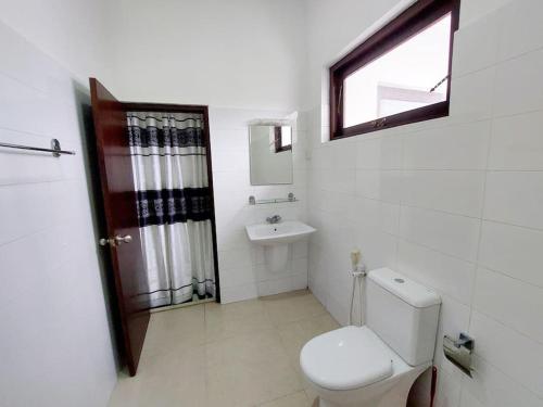 a bathroom with a toilet and a sink and a window at Comfortable Stay in Colombo in Rajagiriya