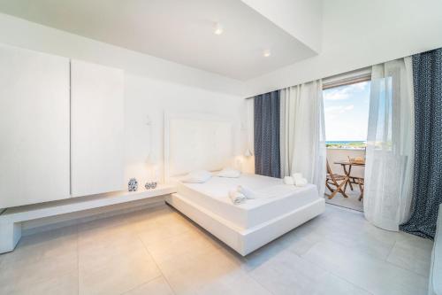 a white bedroom with a tub and a large window at San Giovanni Beach Resort and Suites in Lefkada Town