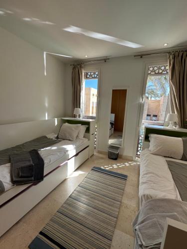 a bedroom with two beds and a large window at Bright & Lovely 2 Beds Apartment in Scarab Club, El Gouna in Hurghada