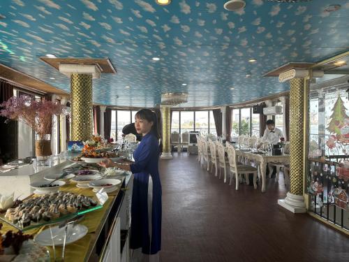 a woman standing at a buffet in a restaurant at Halong AQUAR CRUISE in Ha Long