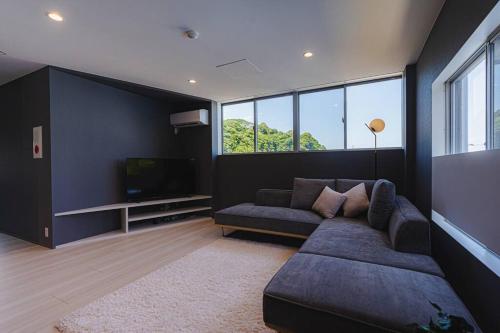 a living room with a couch and a television at unito villa MANAZURU iwakaigan in Manazuru