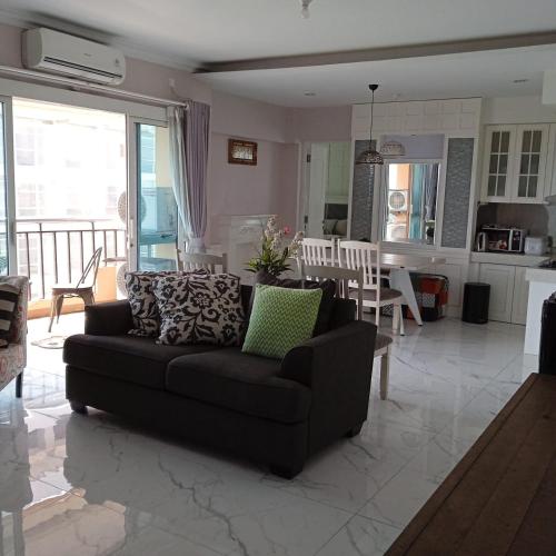 un salon avec un canapé noir et une cuisine dans l'établissement Homey Cozy 3 Bedrooms Apt 125m², à Bandung