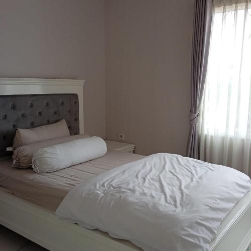 - une chambre avec un lit doté de draps blancs et une fenêtre dans l'établissement Homey Cozy 3 Bedrooms Apt 125m², à Bandung