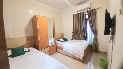 a small room with two beds and a mirror at Homestay Jogja Gejayan Dekat Pakuwon Mall by Simply Homy in Yogyakarta