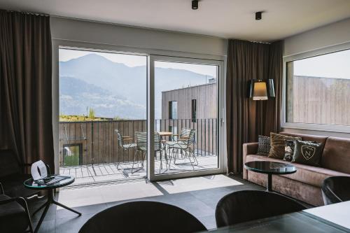 a living room with a couch and a balcony at Nikolaus by AvenidA Panoramic Wellness Suites in Zell am See