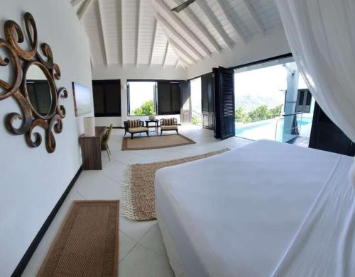 ein Schlafzimmer mit einem Bett und ein Wohnzimmer in der Unterkunft Lux Villa w/ Stunning Panoramic Ocean Views in Bequia