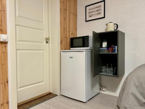 un forno a microonde sopra un frigorifero accanto a una porta di Simple room a Trondheim