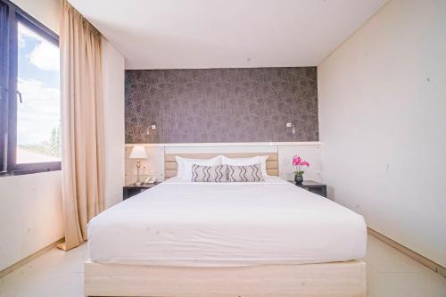 a bedroom with a large white bed and a window at Sahid T-More Hotel in Kupang