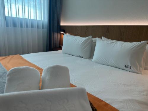 a bed with white pillows and chairs in a room at Chun Yuan Zi in Hu-an-liao