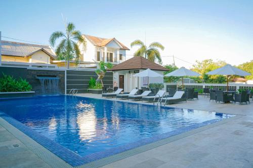 a swimming pool with chairs and a house at Sahid T-More Hotel in Kupang