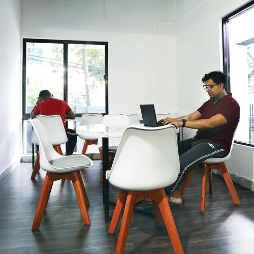 a man sitting at a table using a laptop computer at Yess by bti - Male Hostel in Dhaka