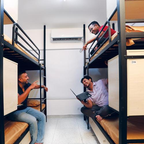 a group of three men sitting on bunk beds at Yess by bti - Male Hostel in Dhaka