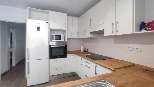 a kitchen with white cabinets and a white refrigerator at Apartamento en Ultramar in Ferrol
