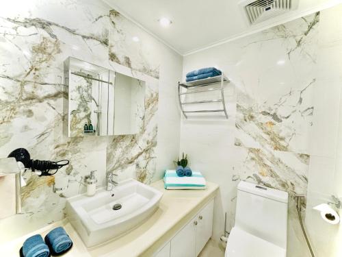 ein Badezimmer mit einem weißen Waschbecken und einer Marmorwand in der Unterkunft Sophisticated Oceanview Studio in La Mirada in Mactan