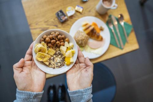 a person holding a bowl of food in front of a table at Krause: deine Wohlfühloase in Zentrum v. Bielefeld in Bielefeld