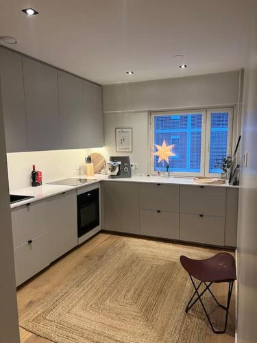 - une cuisine avec des placards blancs et une chaise dans l'établissement Vaasa central apartment, à Vaasa