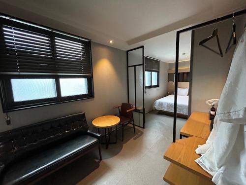 a room with a couch and a table and a bed at Deluxe motel in Geoje 
