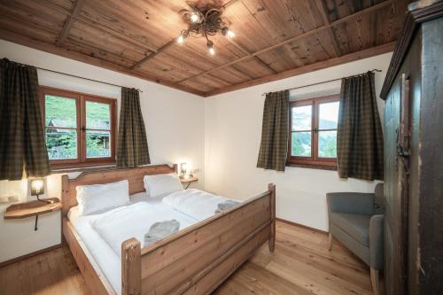 a bedroom with a bed and a chair and windows at Chalet Kleinbretteneben in Grossarl