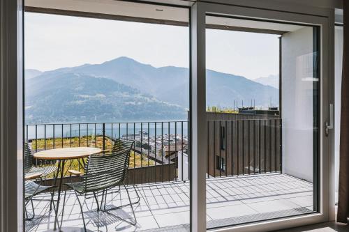 a balcony with a table and chairs and mountains at Nikolaus by AvenidA Panoramic Wellness Suites in Zell am See