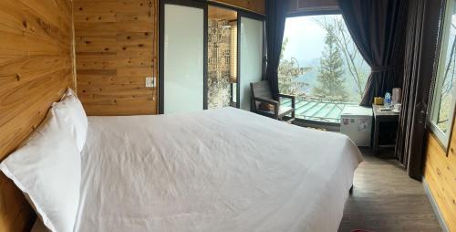 a bedroom with a large white bed and a balcony at Catcat Garden House in Sa Pa