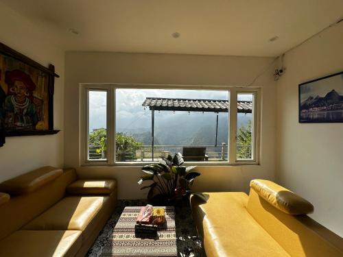 a living room with a couch and a large window at Catcat Garden House in Sa Pa