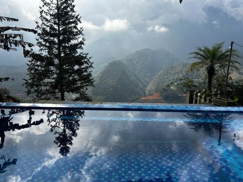 a swimming pool with a tree and mountains in the background at Catcat Garden House in Sa Pa