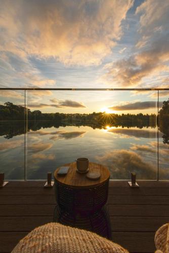 a table on a balcony with a view of a lake at Edge Luxury Villas in Wilyabrup