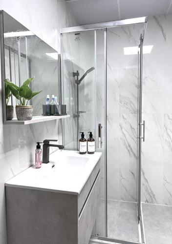 a white bathroom with a shower and a sink at Lake View 1BR Apt Balcony & Near DMCC Metro in Dubai