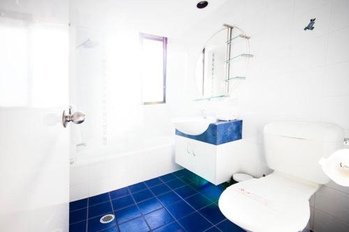 Un baño con inodoro blanco y suelo de baldosas azules. en Warringa Surf Holiday Apartments, en Gold Coast