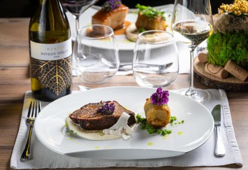 a plate of food on a table with wine glasses at Dobosi Birtokközpont in Szentantalfa
