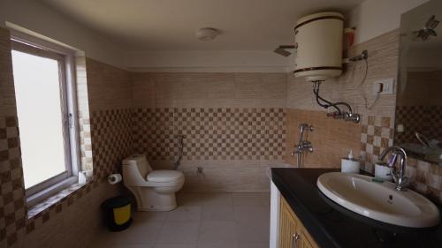 Un baño con lavabo, inodoro y ventana. en BARFI MANALI, en Manali