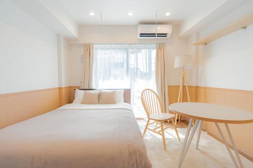 a bedroom with a bed and a table and a window at unito residence HIKAWADAI in Tokyo