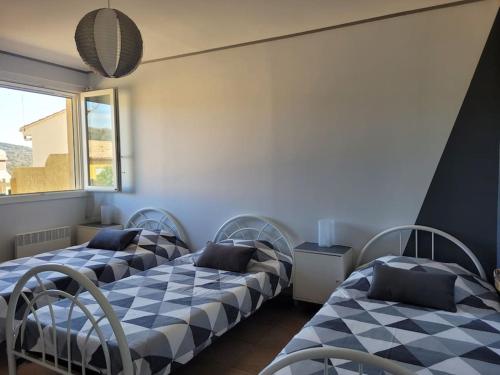 une chambre avec deux lits et une fenêtre dans l'établissement Gîte Le Bel-Estar, à Bélesta