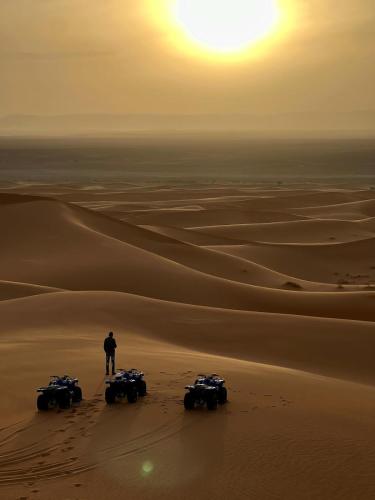a man standing in the desert with four atvs at Camels House in Merzouga